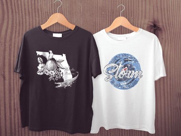 Two Shirts on Hangers, one black and one white, both with graphics printed on the shirt in color
